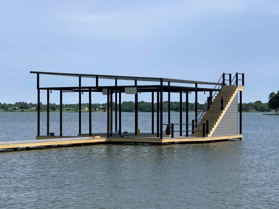 A view from the water of a custom boat ramp and covered deck pictured with stairs