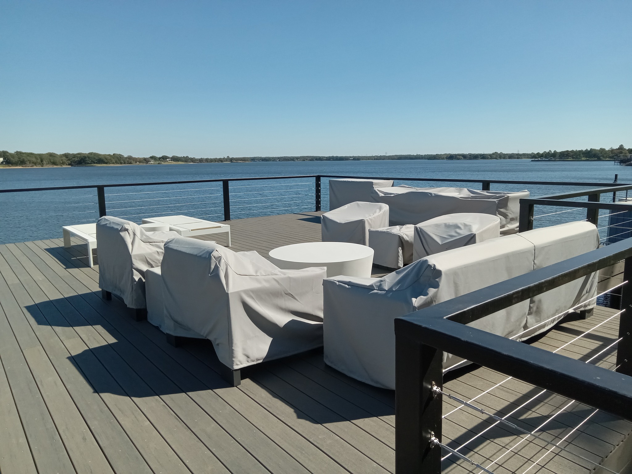 A patio/deck on the water with covered furniture
